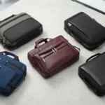 Collection of professional laptop bags and travel briefcases in various colors and styles arranged on a modern concrete surface.