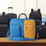 Collection of travel bags and luggage on a wooden table, including a blue and orange laptop bag, black backpacks, and a blue suitcase.