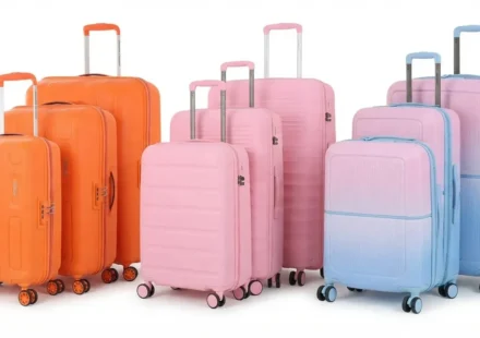 A vibrant collection of colorful orange, pink, and pastel gradient luggage suitcase sets lined up on a white background.