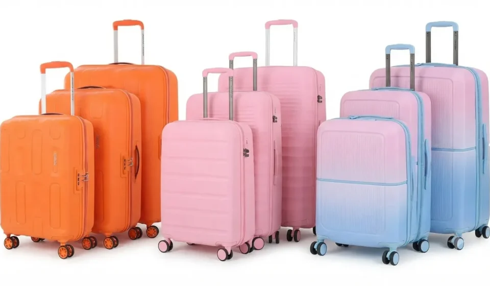 A vibrant collection of colorful orange, pink, and pastel gradient luggage suitcase sets lined up on a white background.