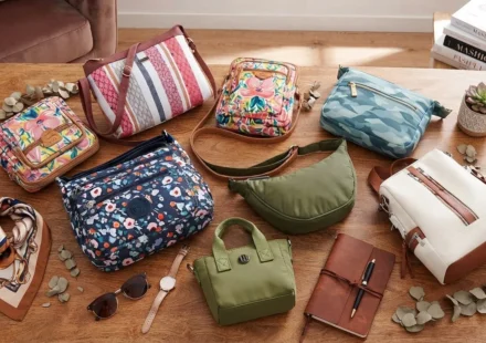 Collection of trendy women's handbags and accessories arranged on a rustic wooden table.